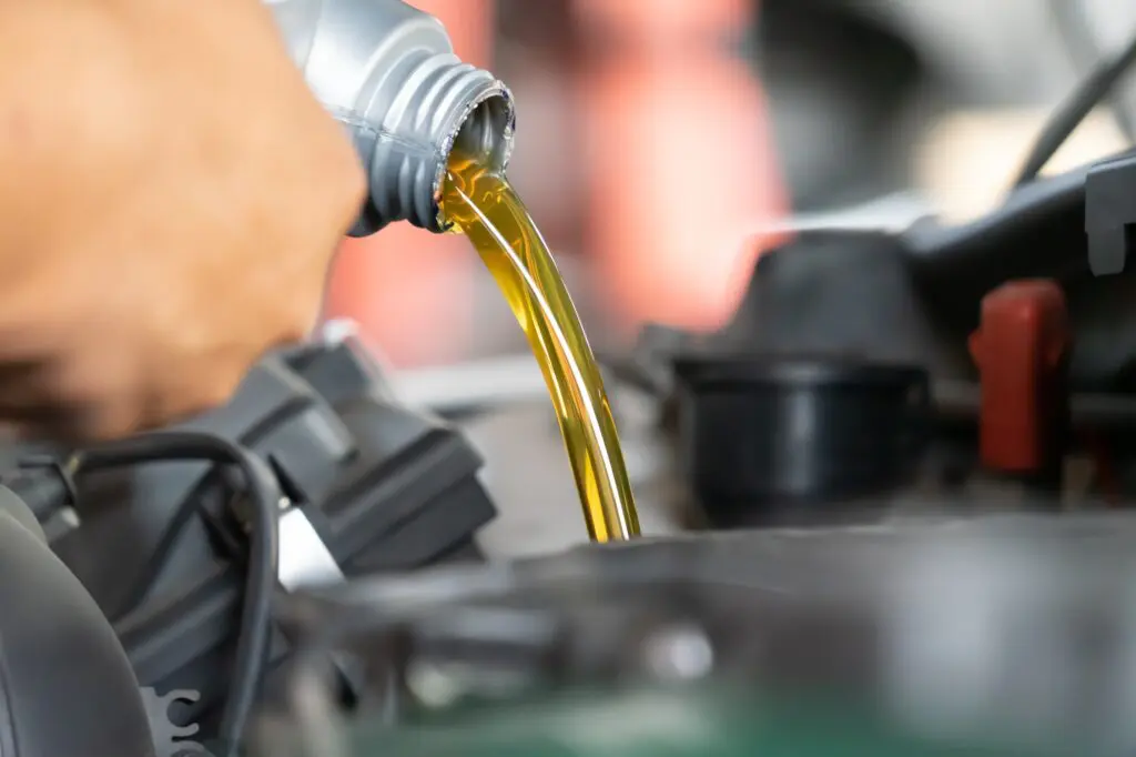 Mechanic pouring engine oil to car engine. Fresh oil poured during an oil change to a car in Red Deer
