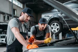 professional manual workers repairing car in mechanic shop