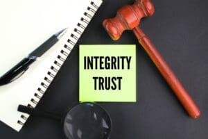 judge's gavel, pen and magnifying glass with the word integrity trust.