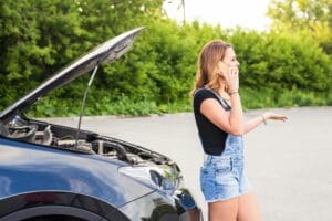 young woman and broken car calling for help on cell phone